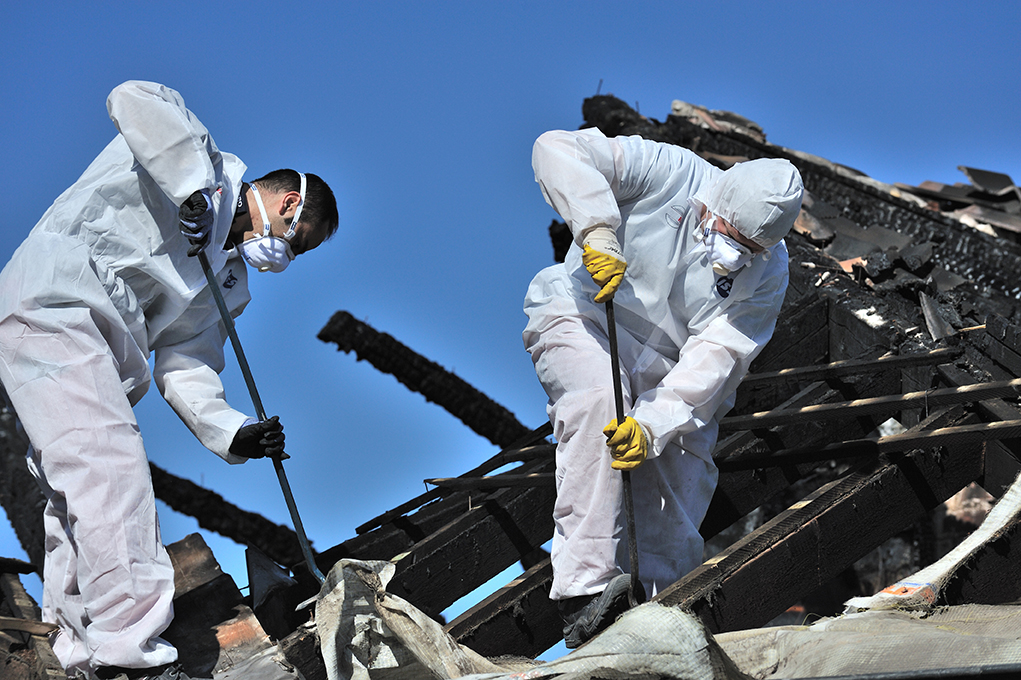 Photo of two men cleaning up on the damage roof